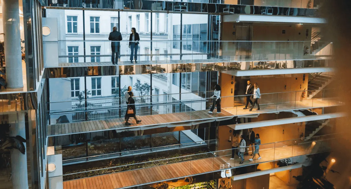 L’atrio di un edificio per uffici, con persone sulle passerelle vetrate tra i piani L’atrio di un edificio per uffici, con persone sulle passerelle vetrate tra i piani
